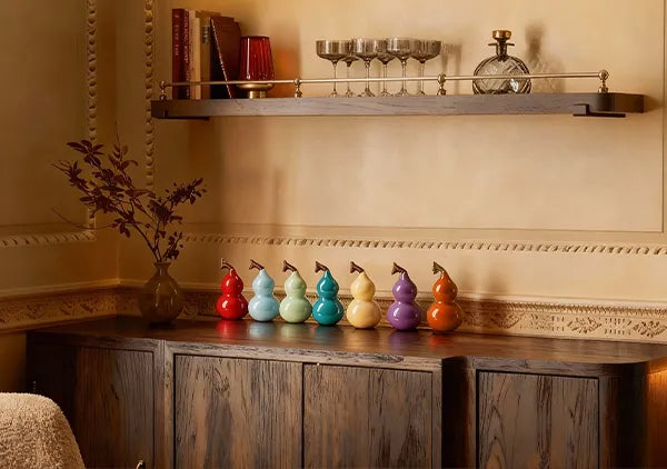 Row of colorful glazed porcelain ornaments styled on a dark wooden sideboard, adding a vibrant pop of color to an elegant dining room interior.
