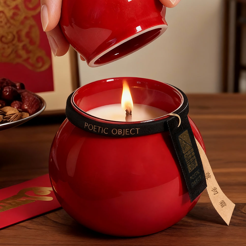 Woman opening the lid of a handcrafted red porcelain candle, a symbol of prosperity and a premium feng shui gift for the home.