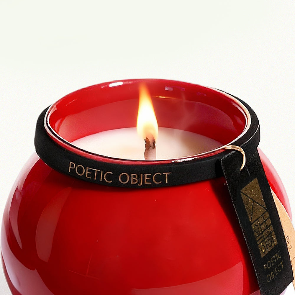 Close-up of a lit luxury aromatherapy candle with a natural wood wick, burning inside a vibrant red Dehua porcelain jar.