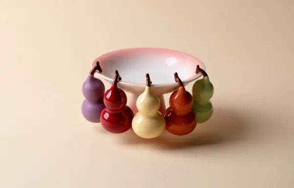 Seven colorful mini porcelain vessels styled on a small white dish, a creative idea for coffee table decor.