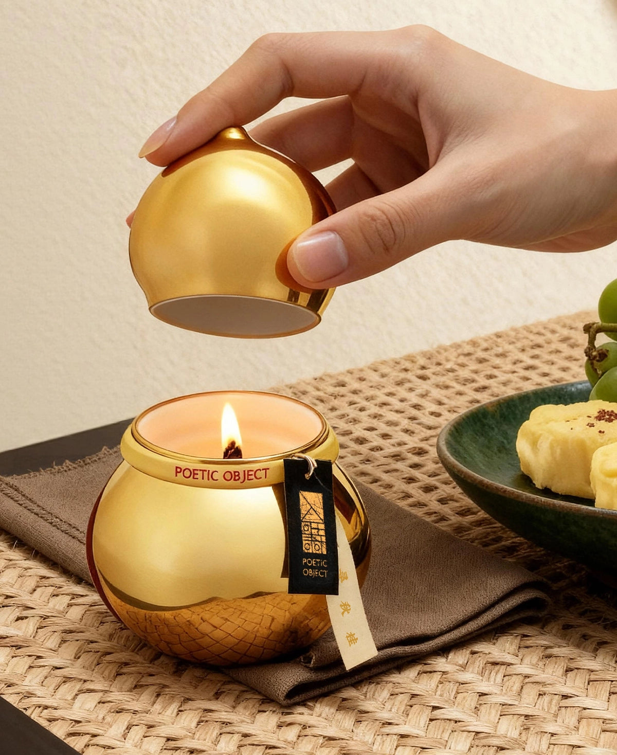 Lifting the gold lid of a lit Golden Osmanthus aroma candle, creating a joyful and opulent atmosphere for home entertaining.
