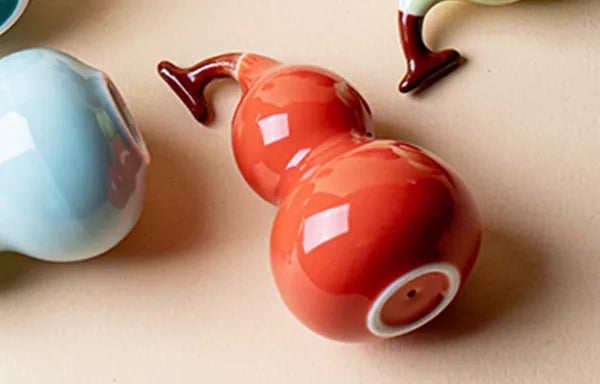 Close-up of Red and Cyan glazed porcelain art pieces, revealing the high-gloss finish and tactile quality.