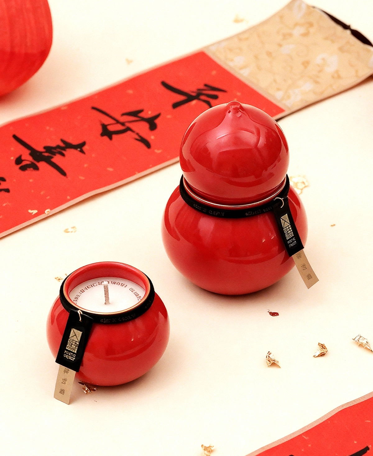 A pair of red Wu Lou shaped porcelain scented candles on a traditional Chinese scroll background, elegant tabletop decor gifts.