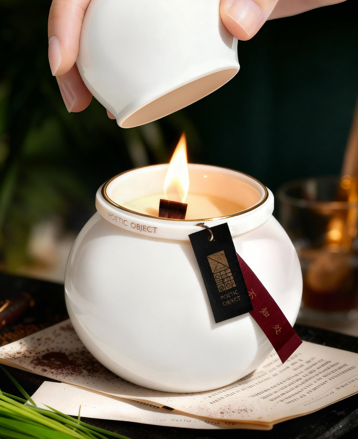 Lit luxury aromatherapy candle in white porcelain jar with wood wick flame and lid, creating a Zen atmosphere.