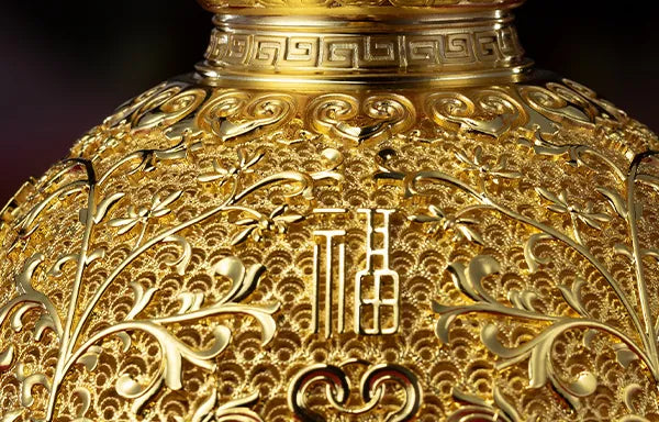 Macro detail of the character "Fu" (Fortune) surrounded by intricate 24K gold filigree patterns on a handcrafted brass art piece.