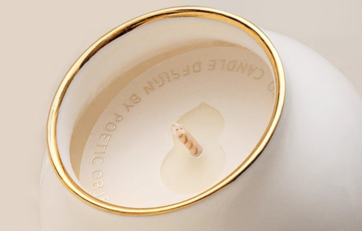 Close-up of natural soy wax candle with wood wick and hand-painted gold rim inside Dehua porcelain vessel.