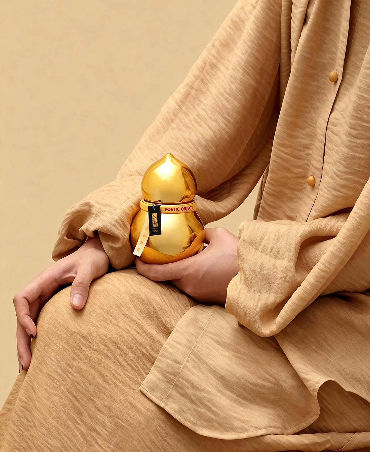 Woman holding a gold mirror-finish porcelain vessel, demonstrating the elegant organic silhouette of a luxury home decor accent.